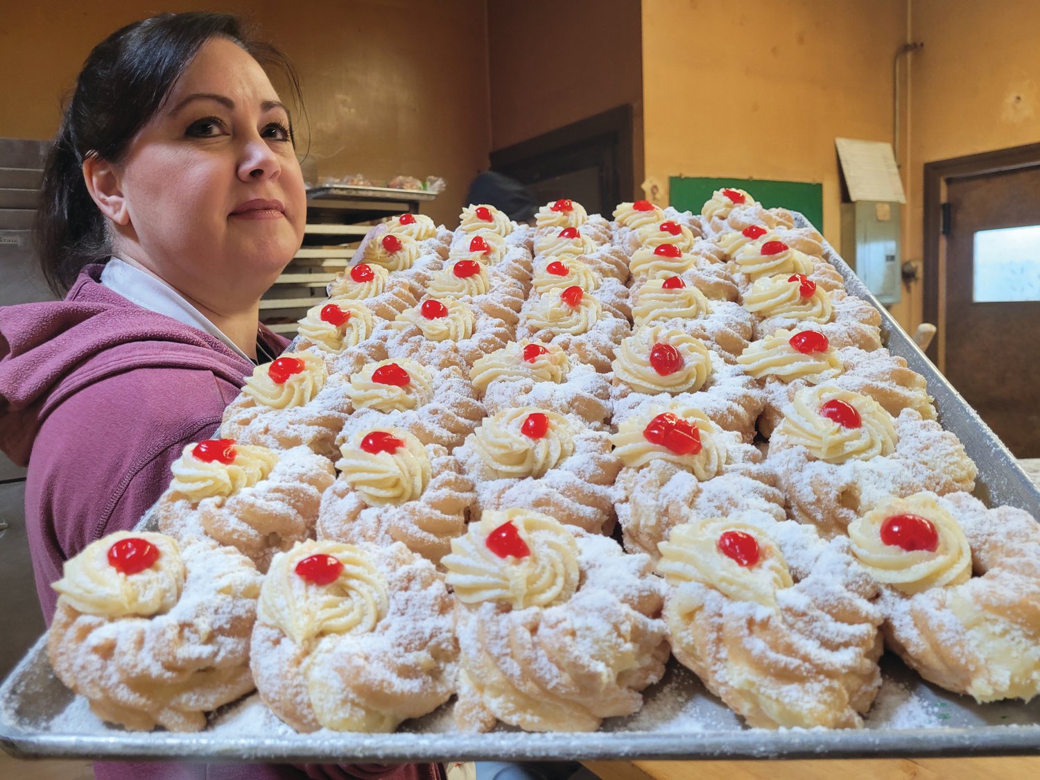 FULLY STOCKED: Diane Notarianni carries a tray of finished zeppoles from the kitchen to the display cases at Solitro’s Bakery, 1594 Cranston St., Cranston.